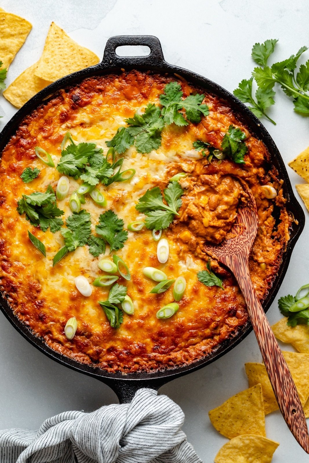 chicken enchilada dip in a skillet with a wooden spoon