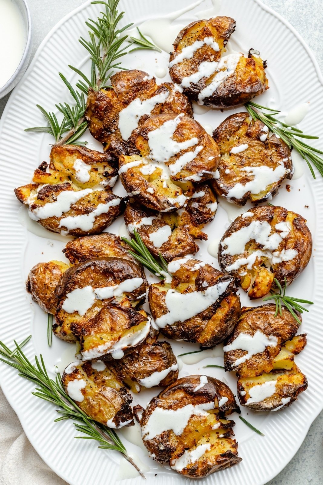 crispy smashed potatoes on a platter drizzled in sauce