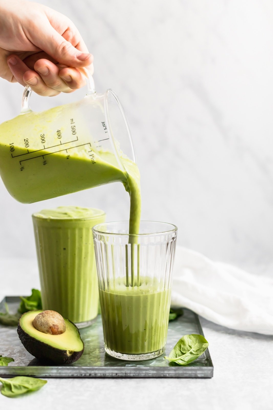 pouring a green smoothie into a glass